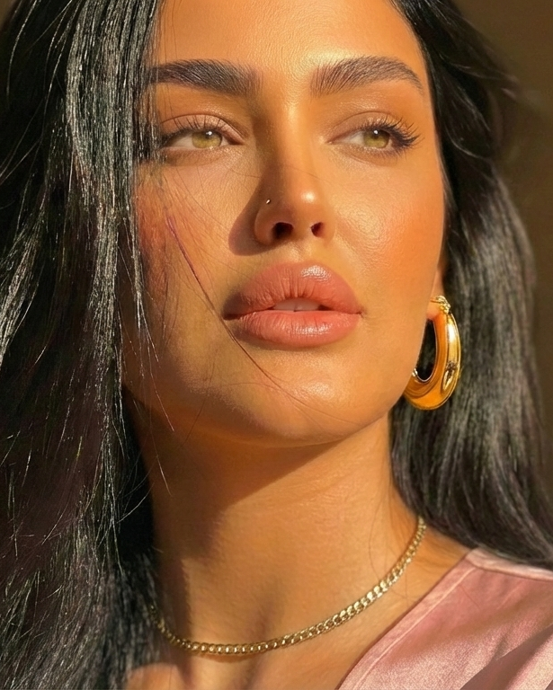 Woman with hoop earrings and a pink top against a neutral background
