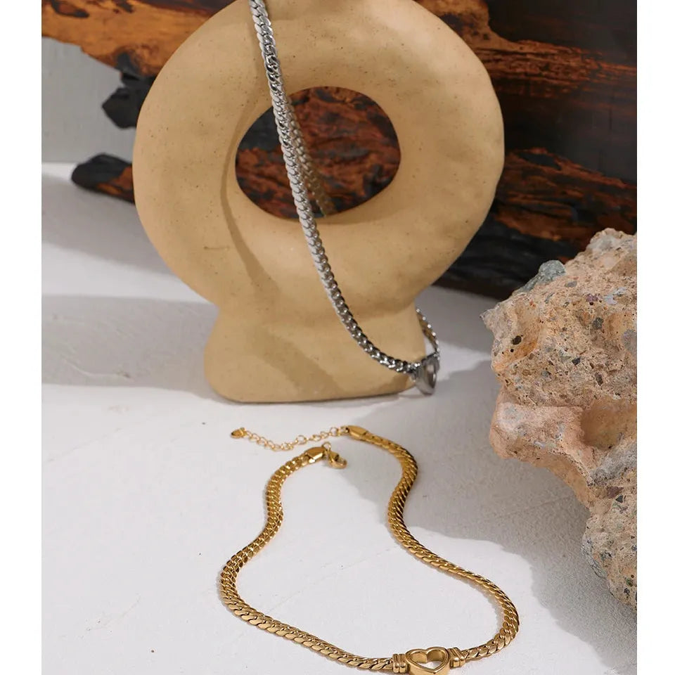 Gold and silver chains on a wooden stand with a natural rock background