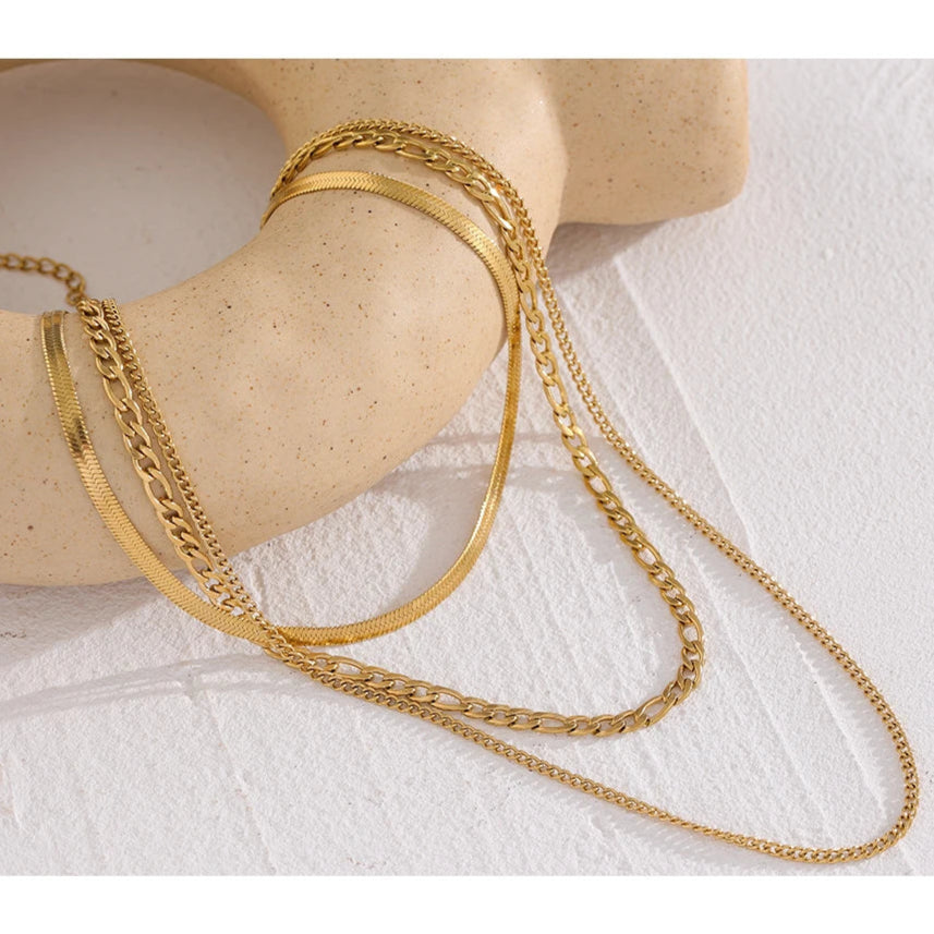Gold chain necklace on a mannequin arm against a white background