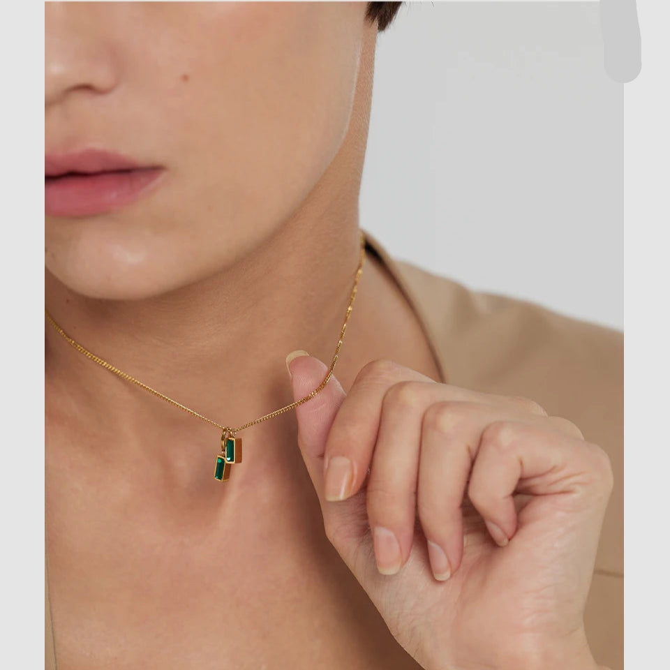 Necklace with a green pendant worn by a person, with 'exquisite' text on the side.