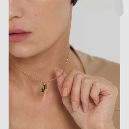 Necklace with a green pendant worn by a person, with 'exquisite' text on the side.