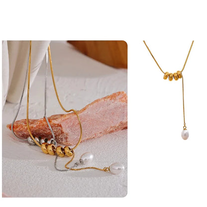 Gold necklace with pearl pendants on a textured surface