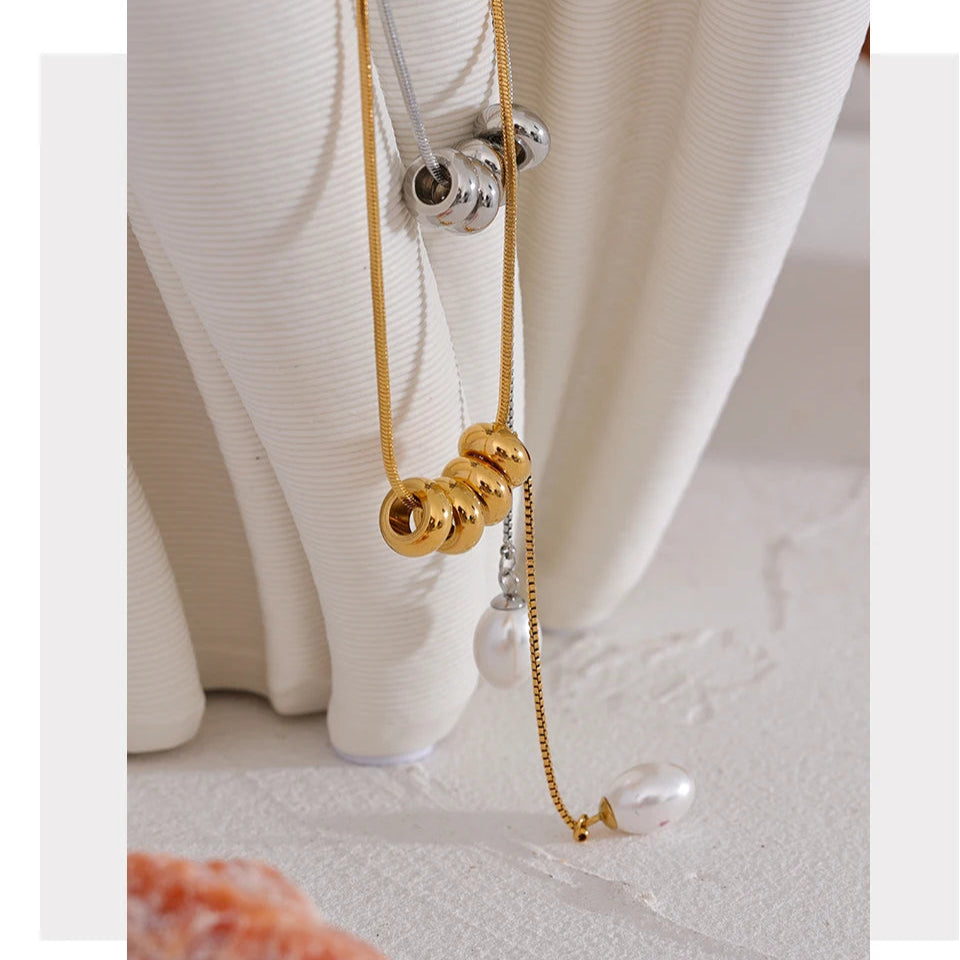 Gold necklace with pearl pendant on a white surface